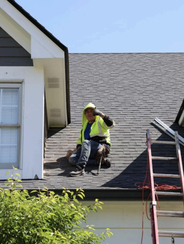 Contractor performing roof repair on residential home with safety gear and ladder – reliable home improvement service.
