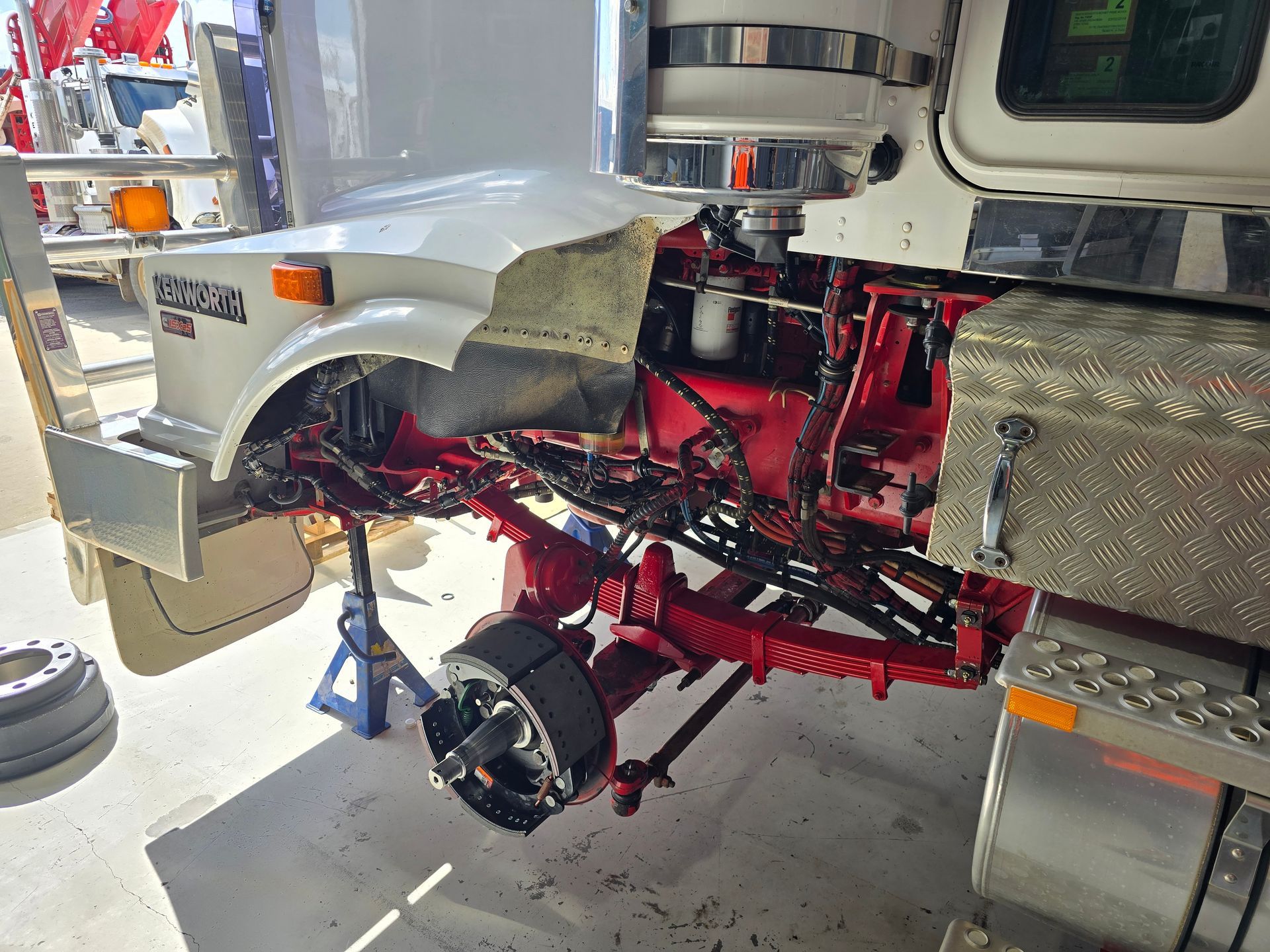 Truck undergoing repair with front end disassembled, supported by jack stands.