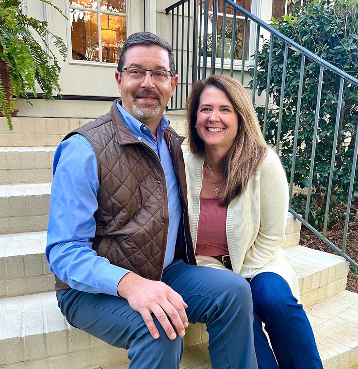 A man and a woman are sitting on the steps of a house.