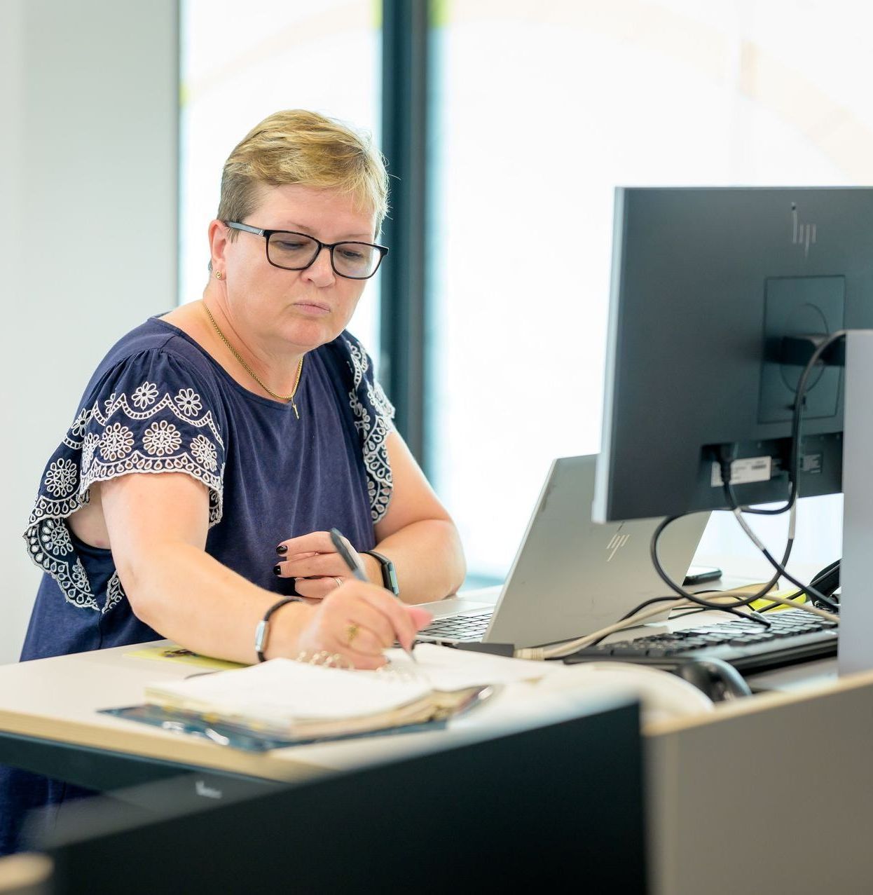 A woman is sitting at a desk in front of a computer.