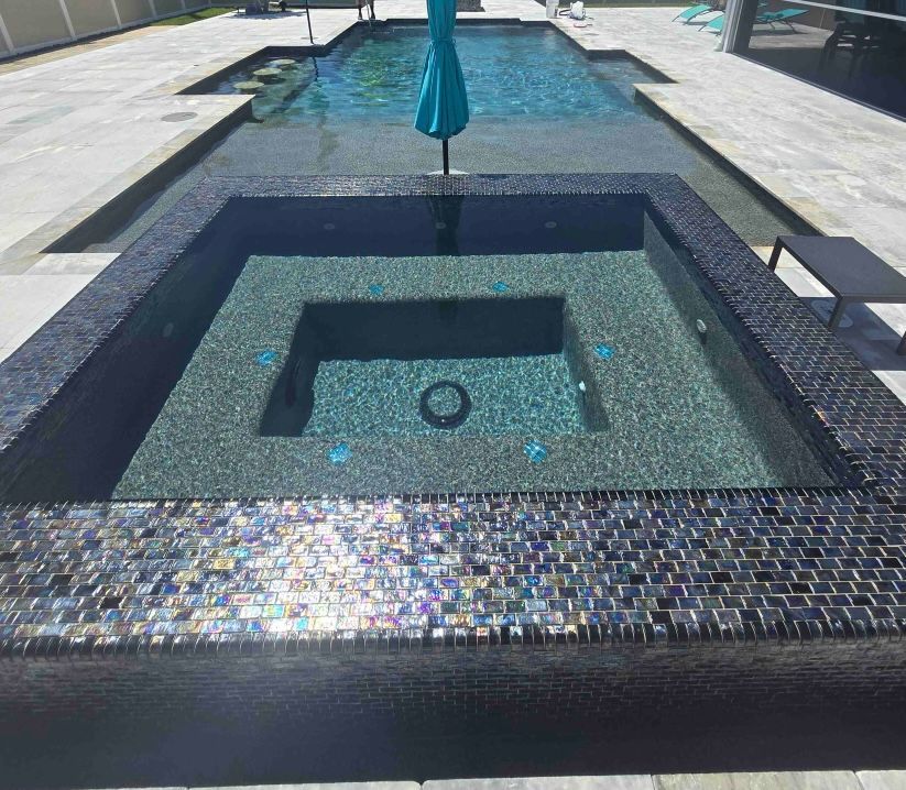 Modern tiled fountain with a square recessed basin and a closed blue umbrella in the center