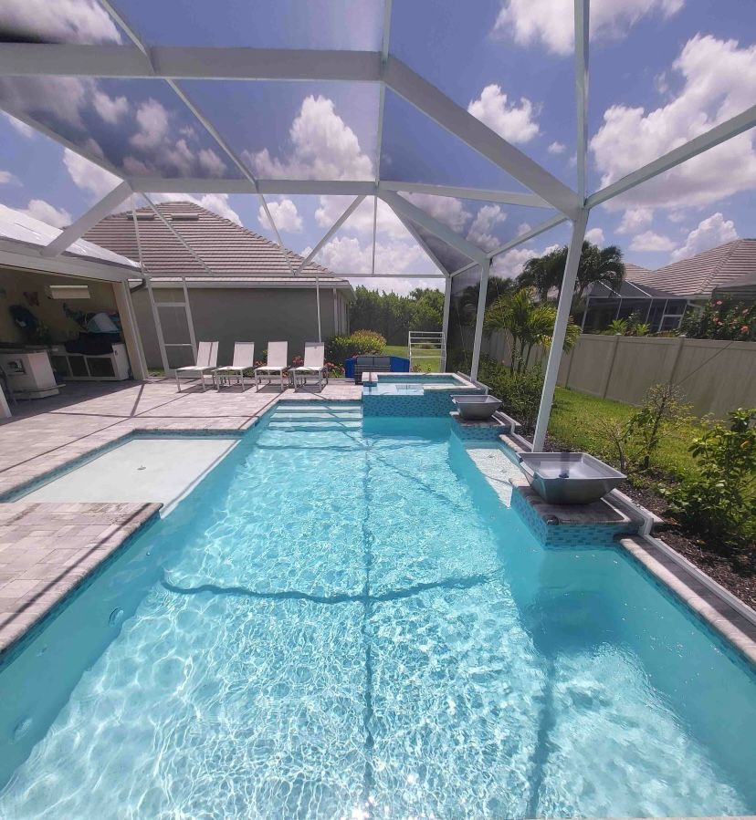 Sunny backyard pool with a screened enclosure, lounge chairs, and clear blue water