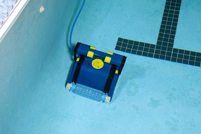 A blue and yellow robot is sitting on the floor of a swimming pool
