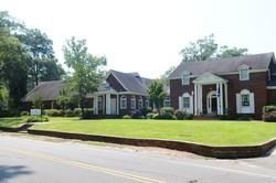 Single-story brick homes with white columns along a grassy suburban street