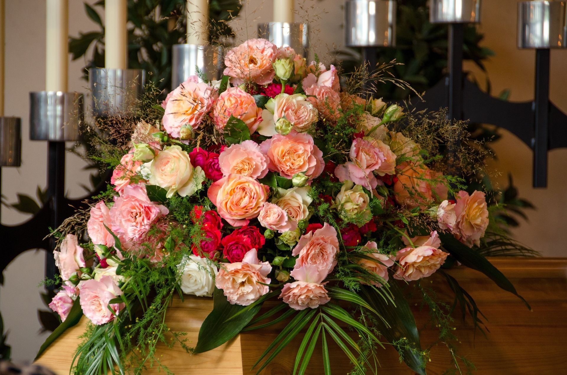 Pink and peach flower arrangement with greenery on a table in a formal indoor setting
