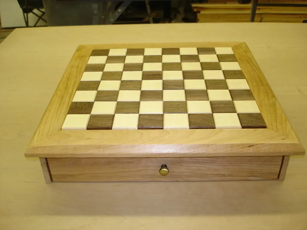 Wooden chessboard box with a drawer, resting on a table