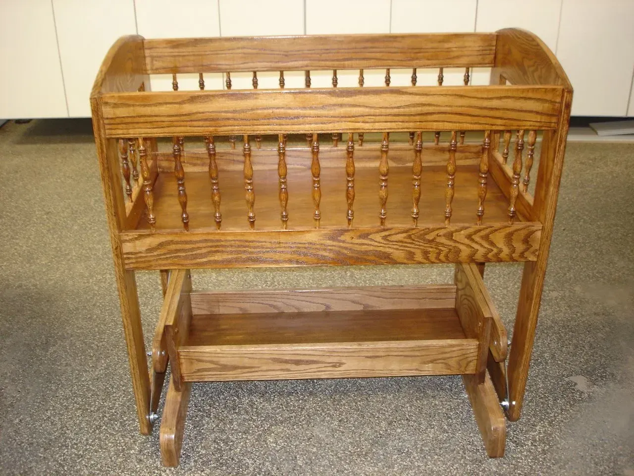 Wooden wicker magazine rack on a carpeted floor against a beige wall