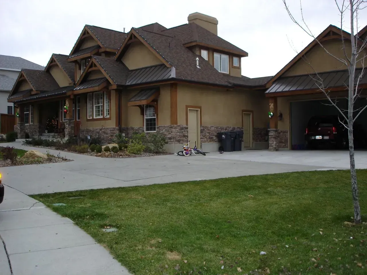 Suburban house with brown siding, attached garage, and a driveway beside a green lawn