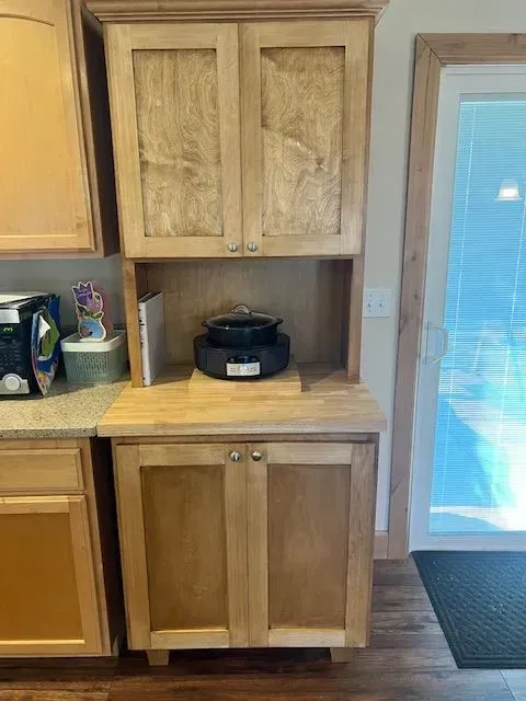 Wooden kitchen cabinets with a countertop and a black countertop appliance beside a sliding glass door.