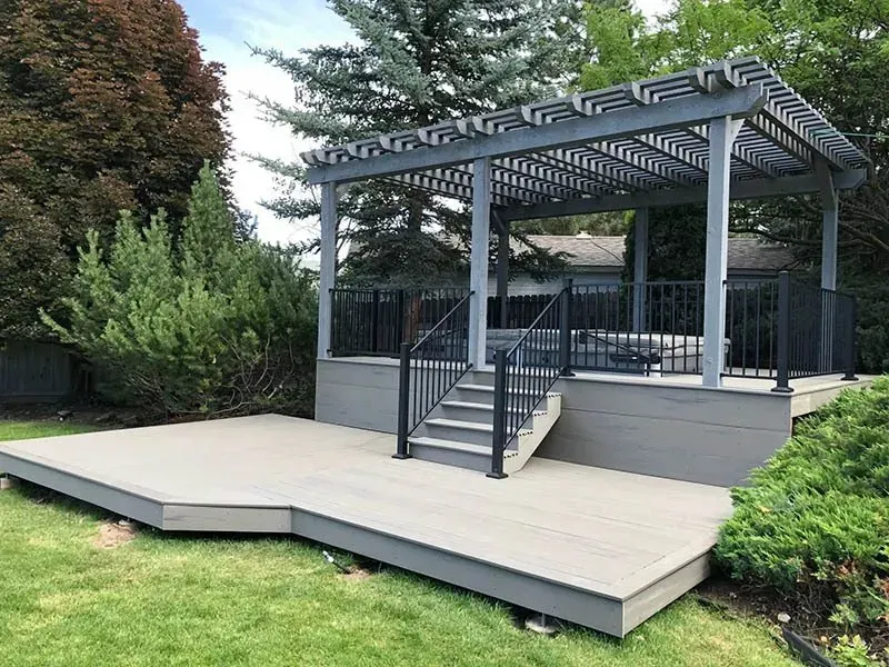 Gray gazebo with stairs and ramp on a raised deck in a landscaped yard
