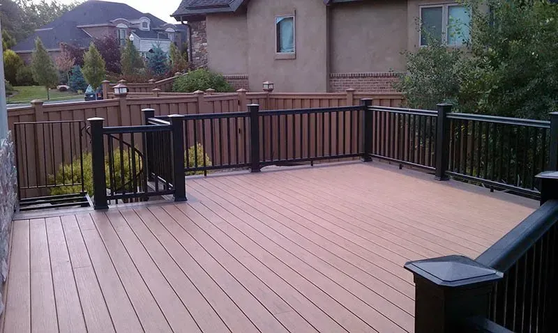 Backyard wooden deck with black railing and view of neighboring houses and hills