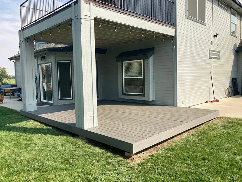 Modern house patio with gray deck, white support column, and grassy yard