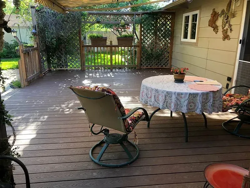 Backyard deck with patio table, chairs, and pergola-covered fence area