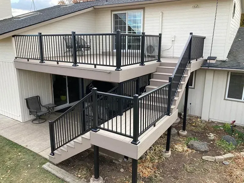 Two-level house deck with black railings and stairs on the back patio