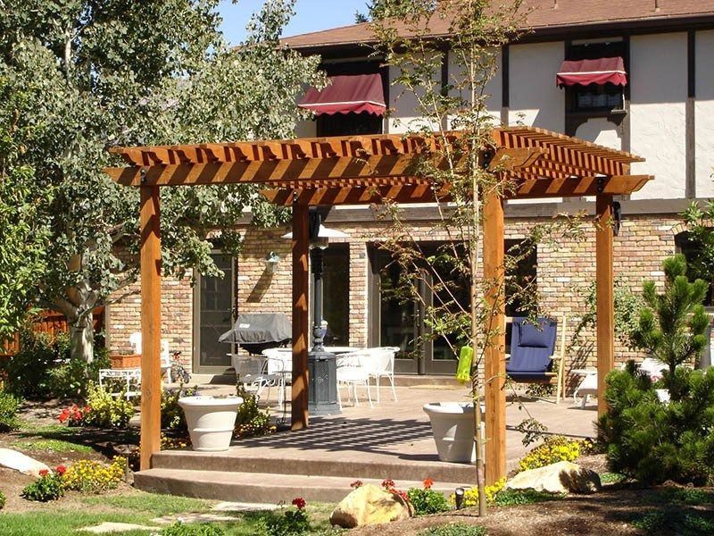A wooden pergola over a patio with outdoor furniture.