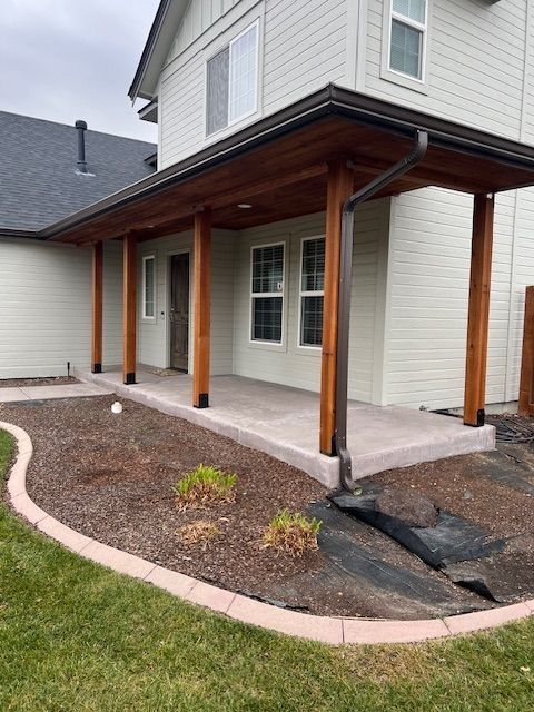Covered front porch with wooden posts and a cracked walkway beside a suburban house.