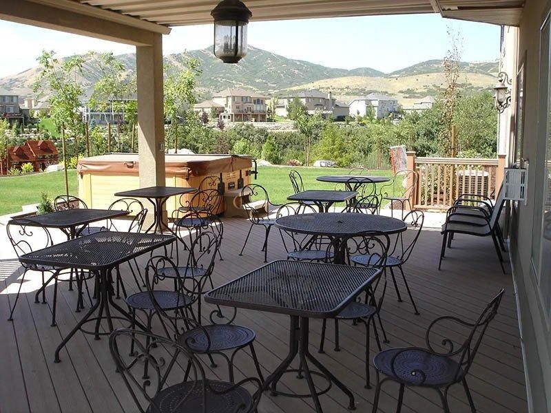 An outdoor deck with metal patio furniture and a hot tub overlooking a hilly landscape.