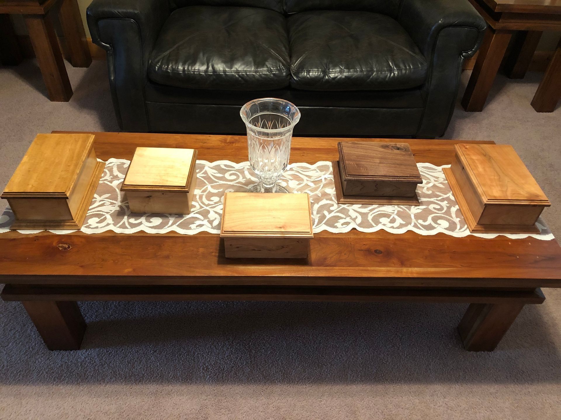 Wooden coffee table with a lace runner, glass vase, and folded cloths in a living room
