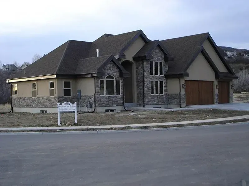 Suburban stone-and-brick house with a garage beside a paved street