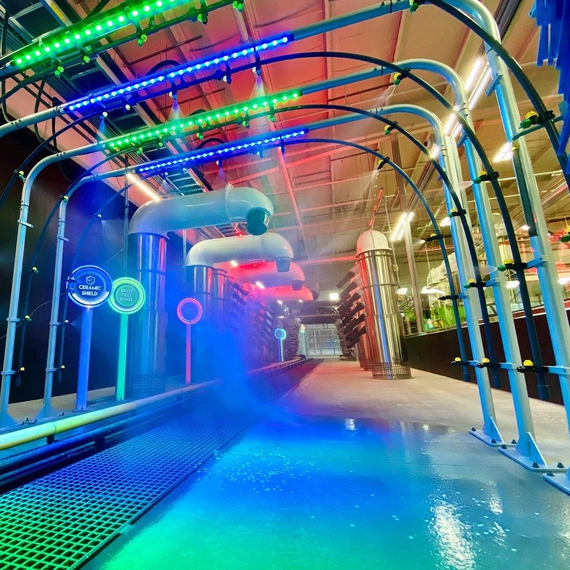 A car wash tunnel with a lot of pipes and lights on it