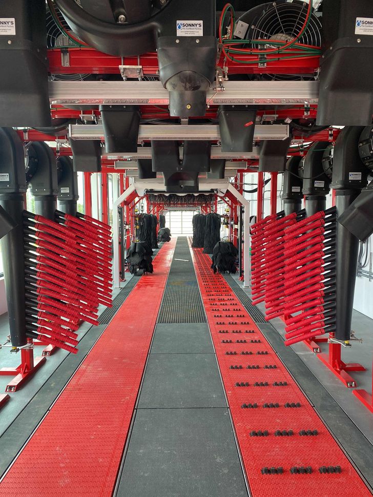 The inside of a car wash with red brushes on the floor