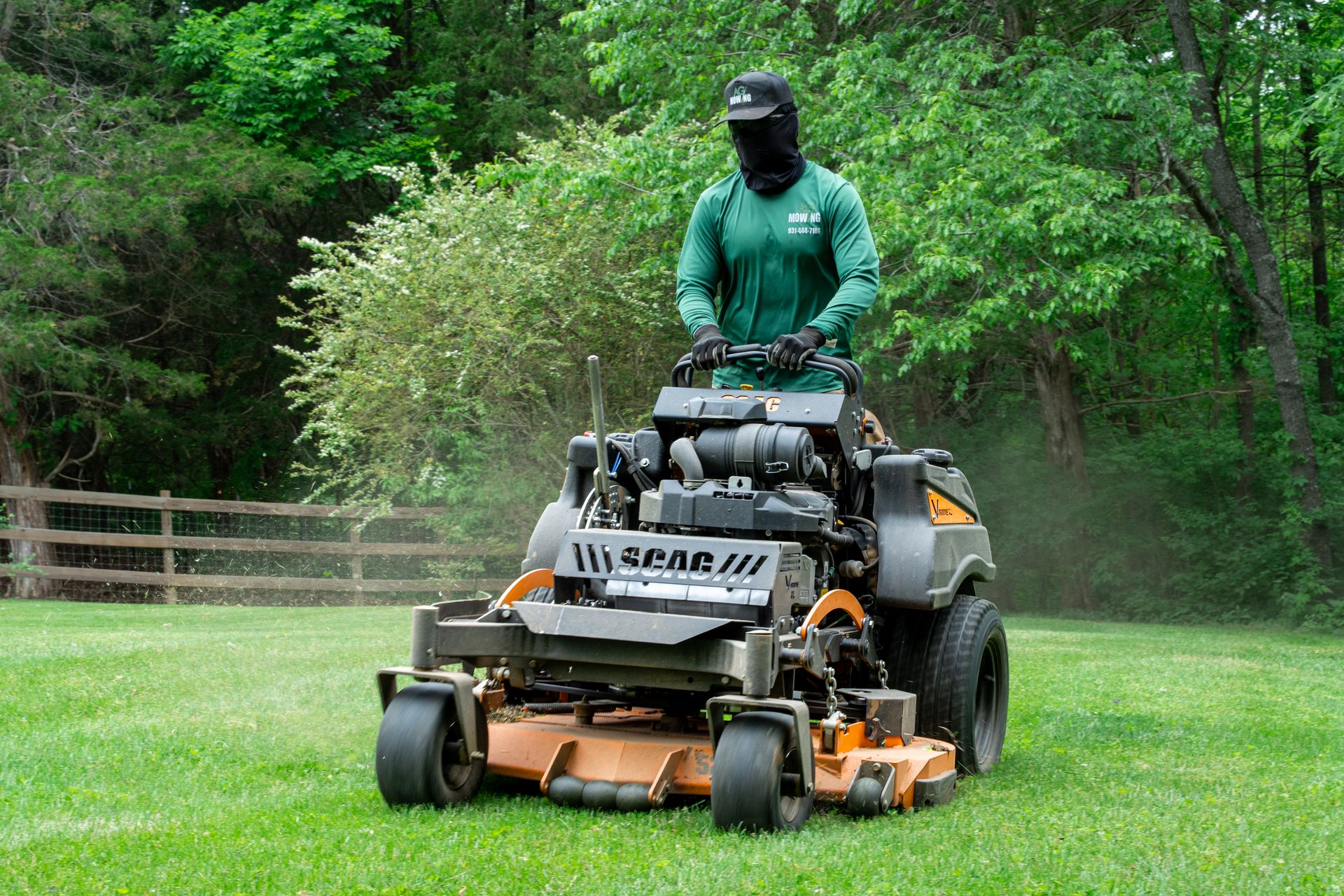 Person on a riding mower cutting grass in a green yard