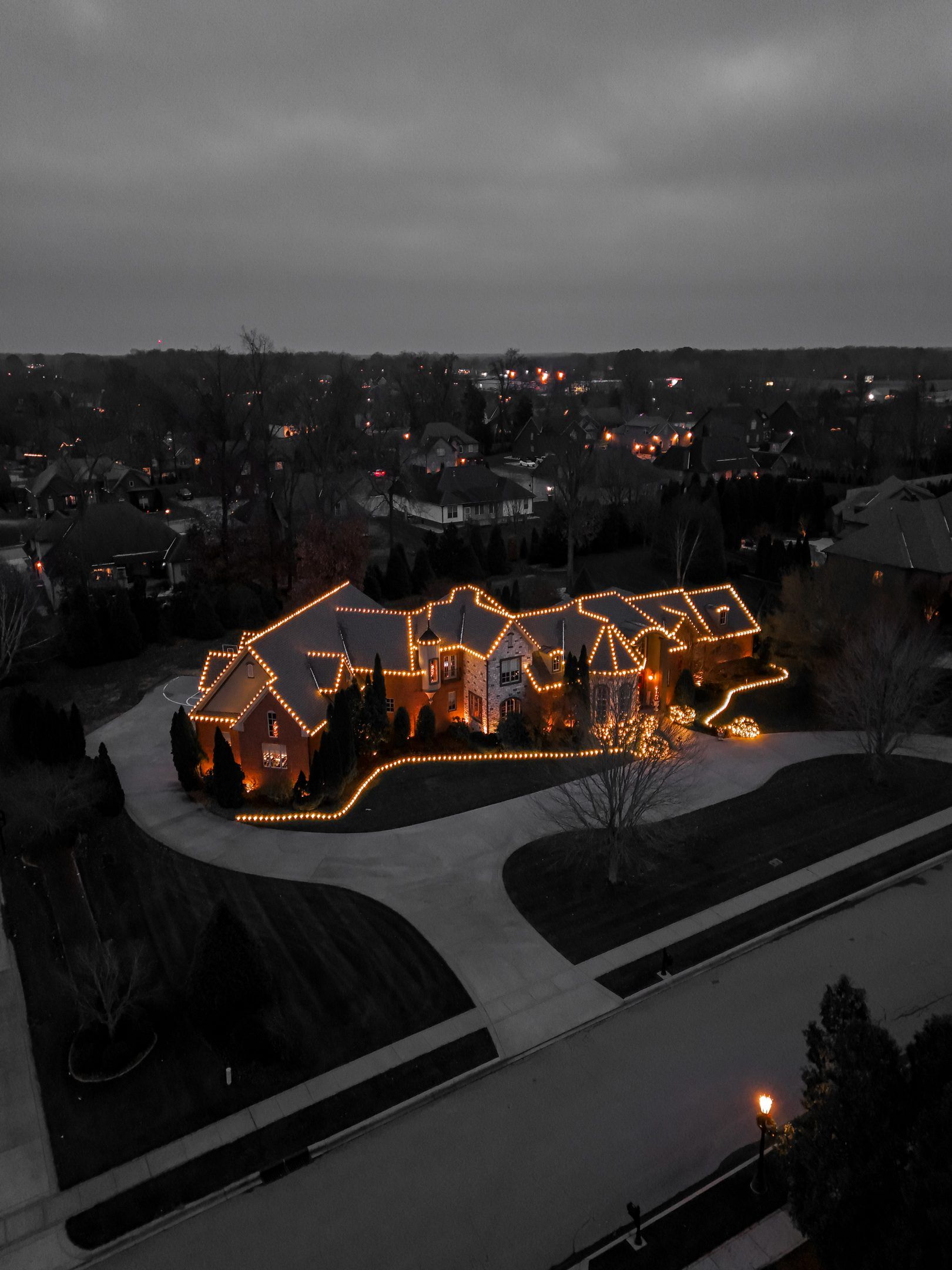 Large house at dusk with holiday lights.