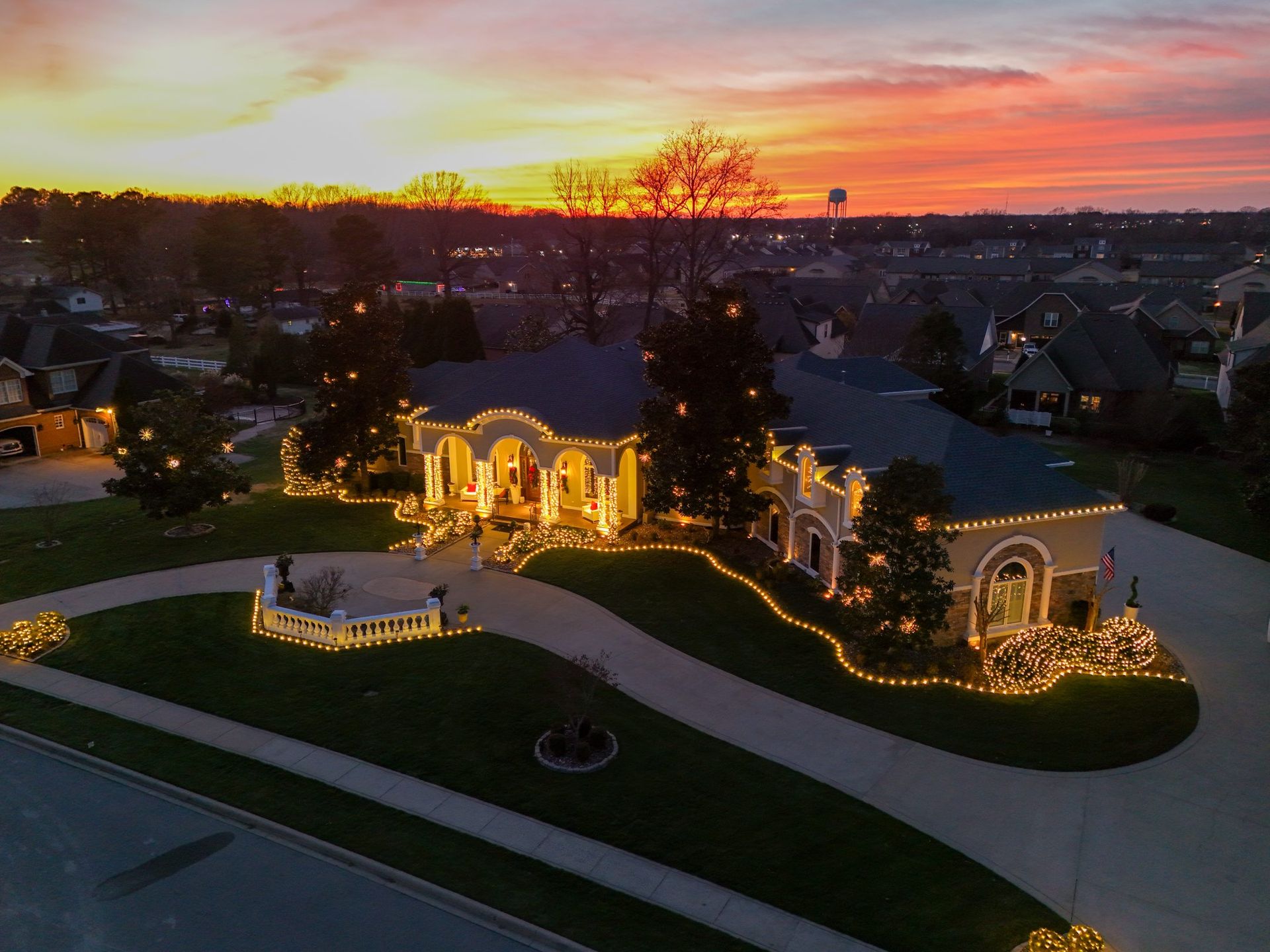 House with bright Christmas lights against a colorful sunset.