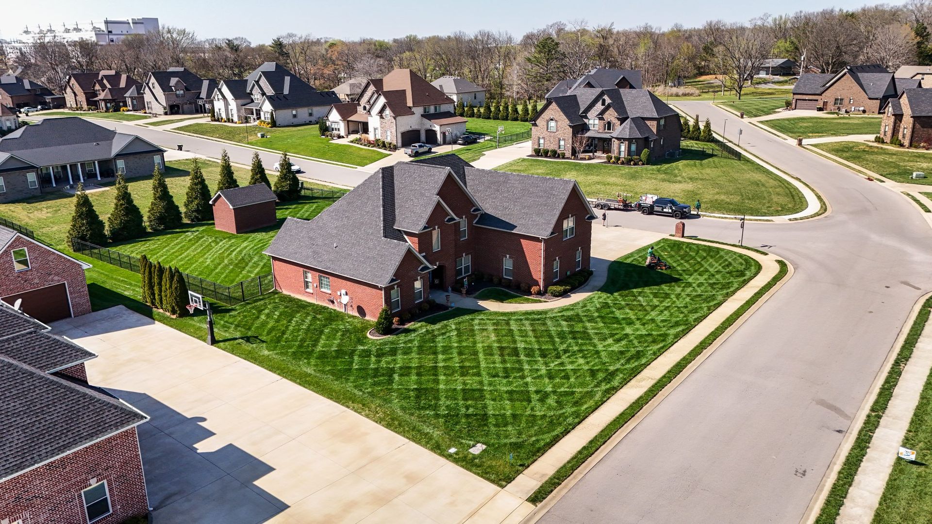 Aerial view of suburban houses with manicured lawns and a curved street in a quiet neighborhood
