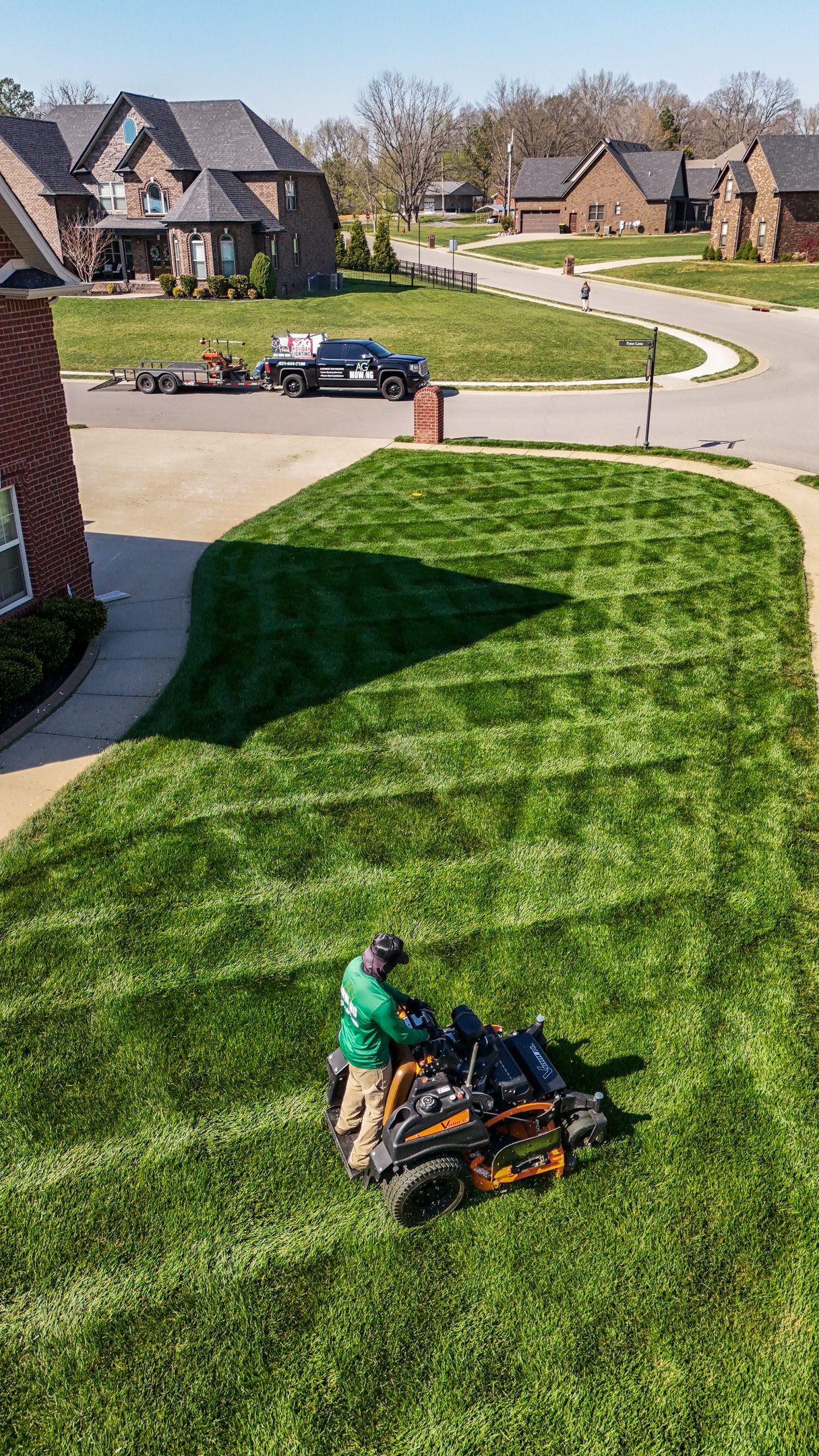 A man is riding a lawn mower on a lush green lawn.