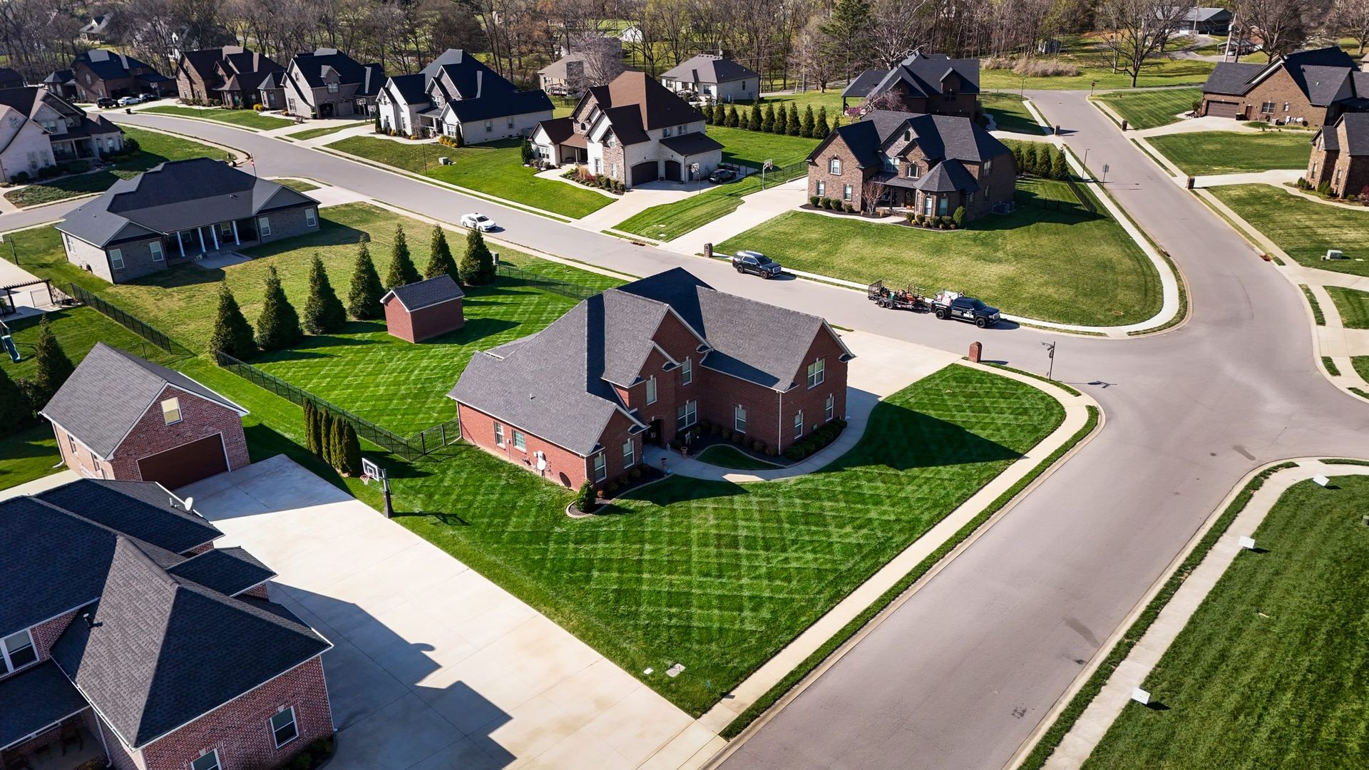 Aerial view of a suburban neighborhood with brick houses, green lawns, and curving streets.
