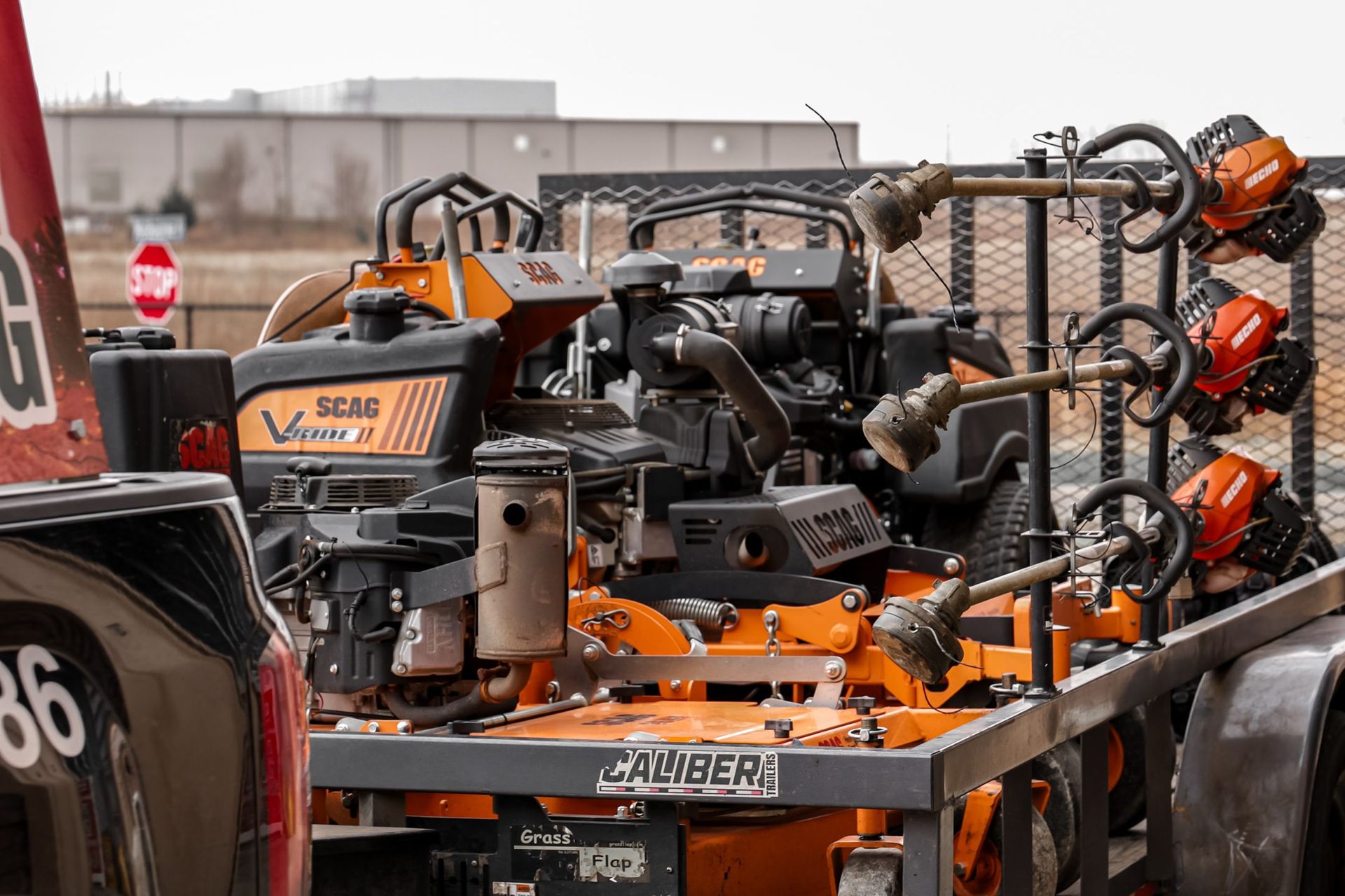 Orange and black lawn care equipment, including a zero-turn mower, on a trailer.