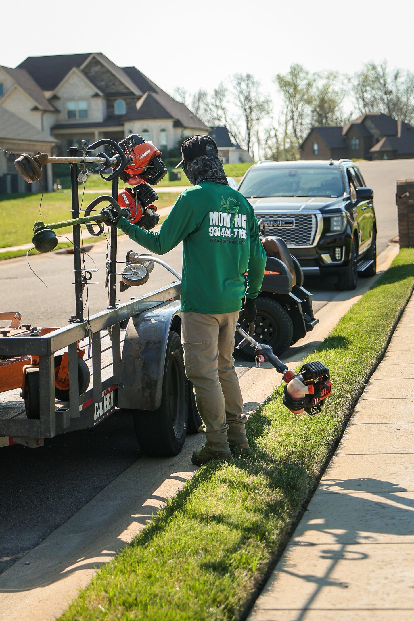 Worker loading bicycles onto a trailer beside a black SUV on a suburban street
