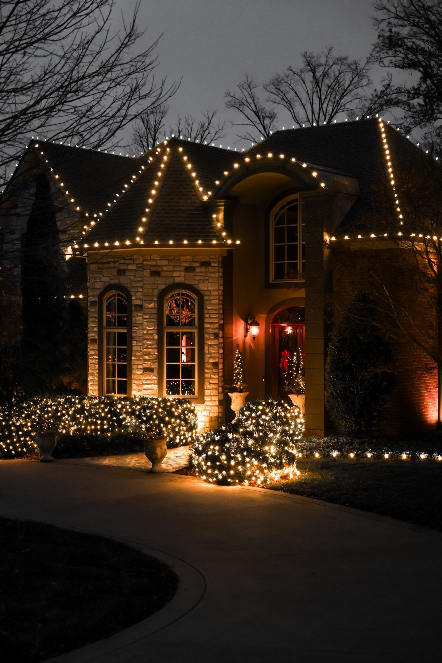 A large house with christmas lights on it is lit up at night.