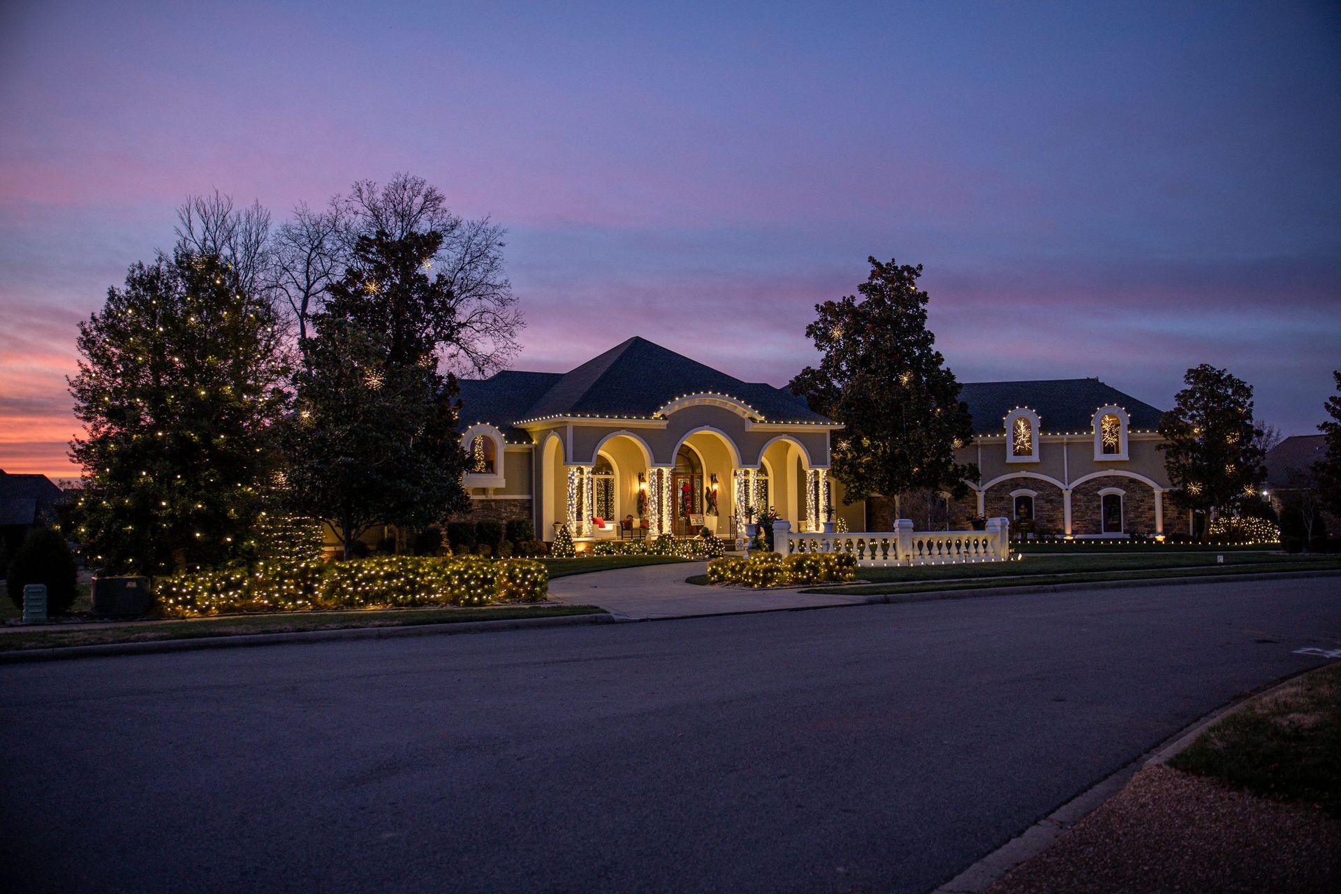 Large house lit with Christmas lights at dusk.