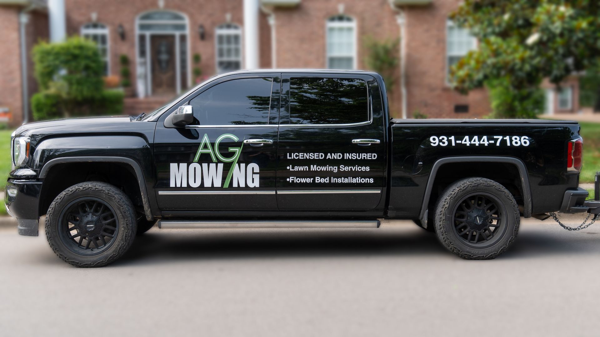 A black truck is parked on the side of the road in front of a house.