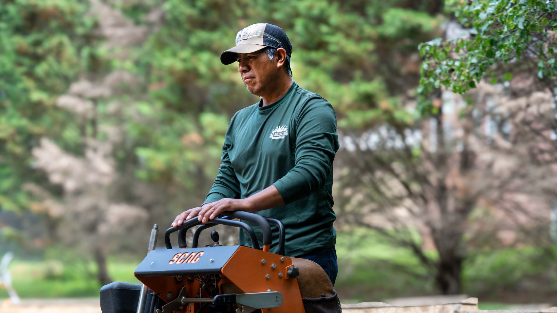 A man is riding a lawn mower in a park.