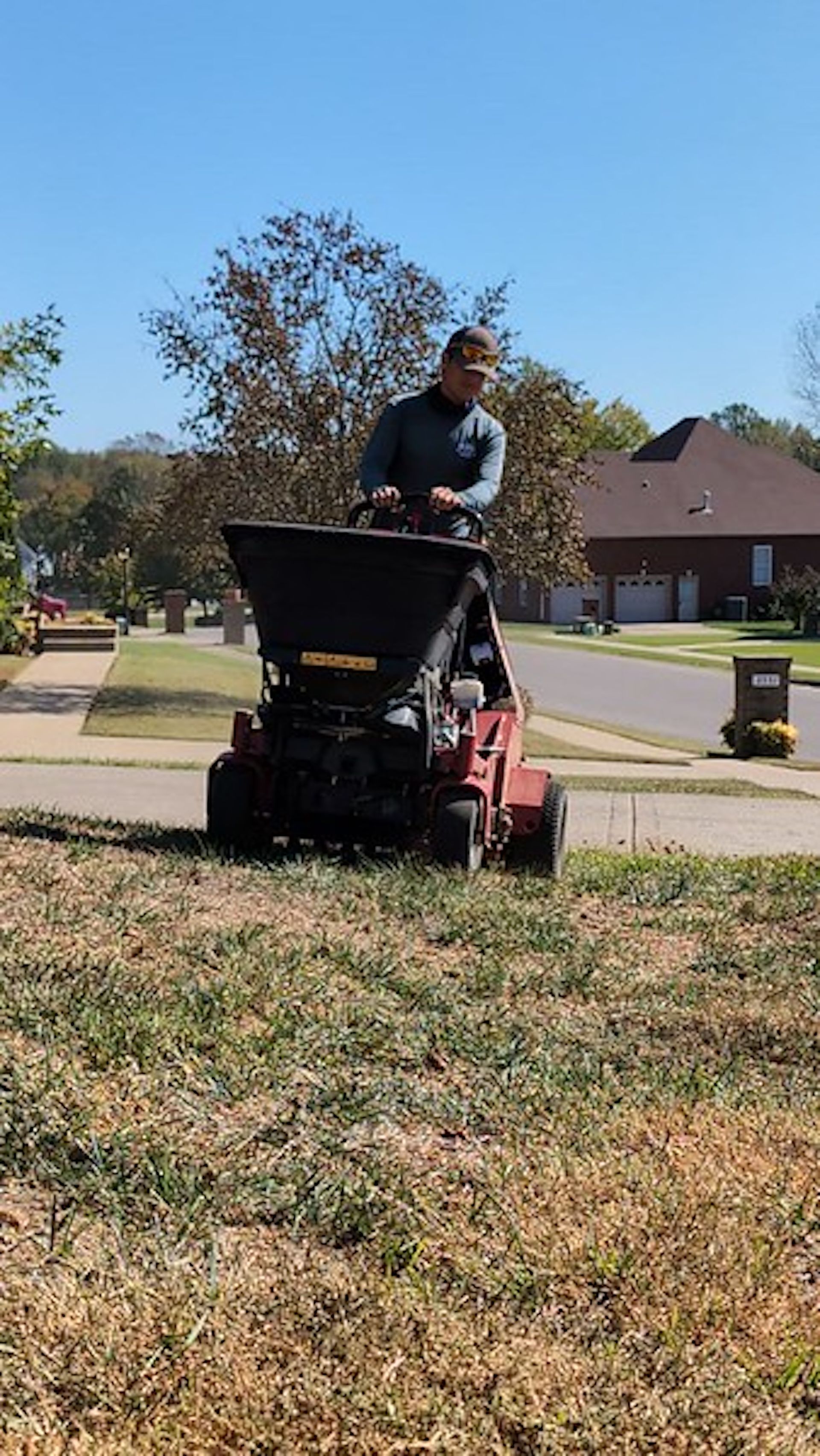 A man is riding a lawn mower in a yard.