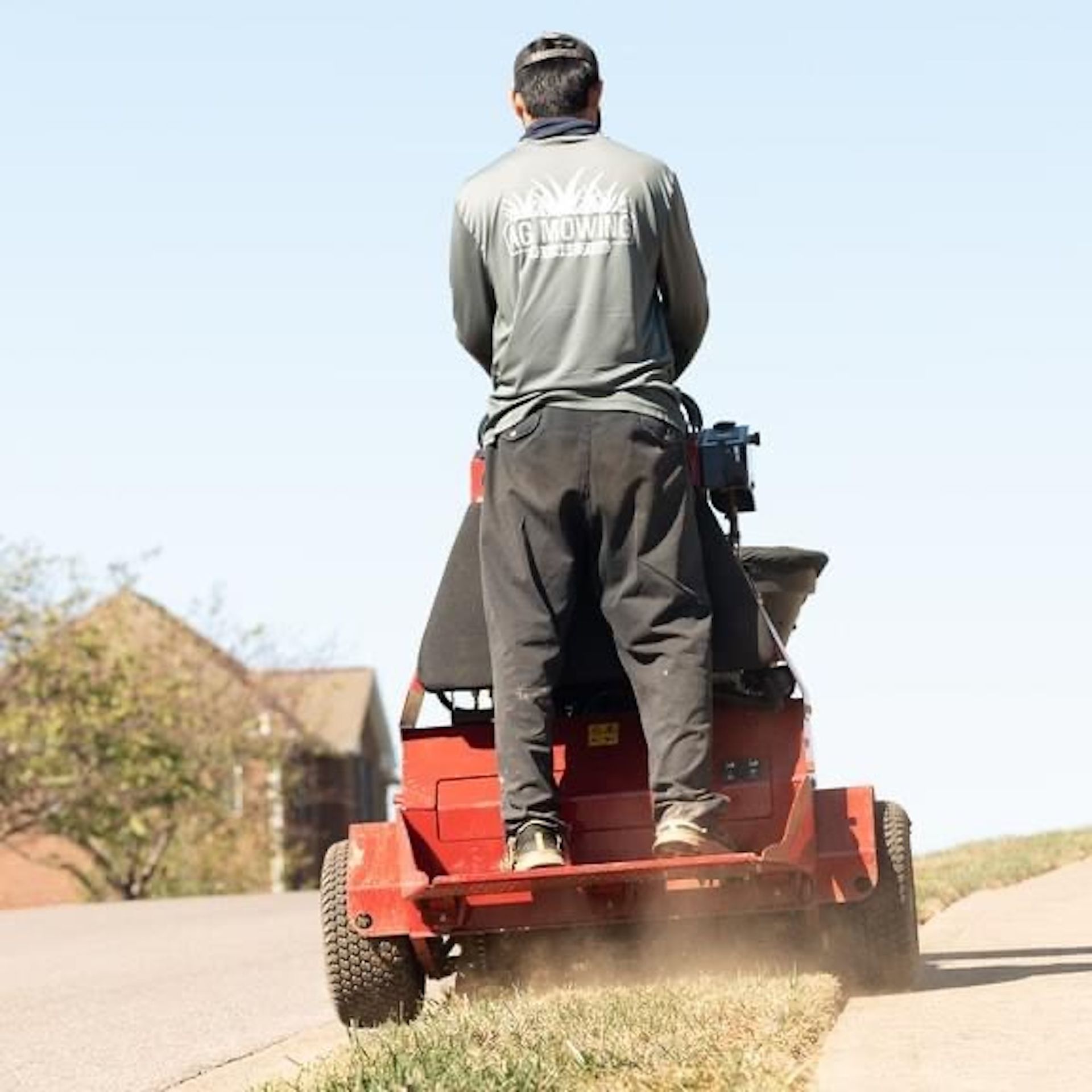 A man is riding a red lawn mower