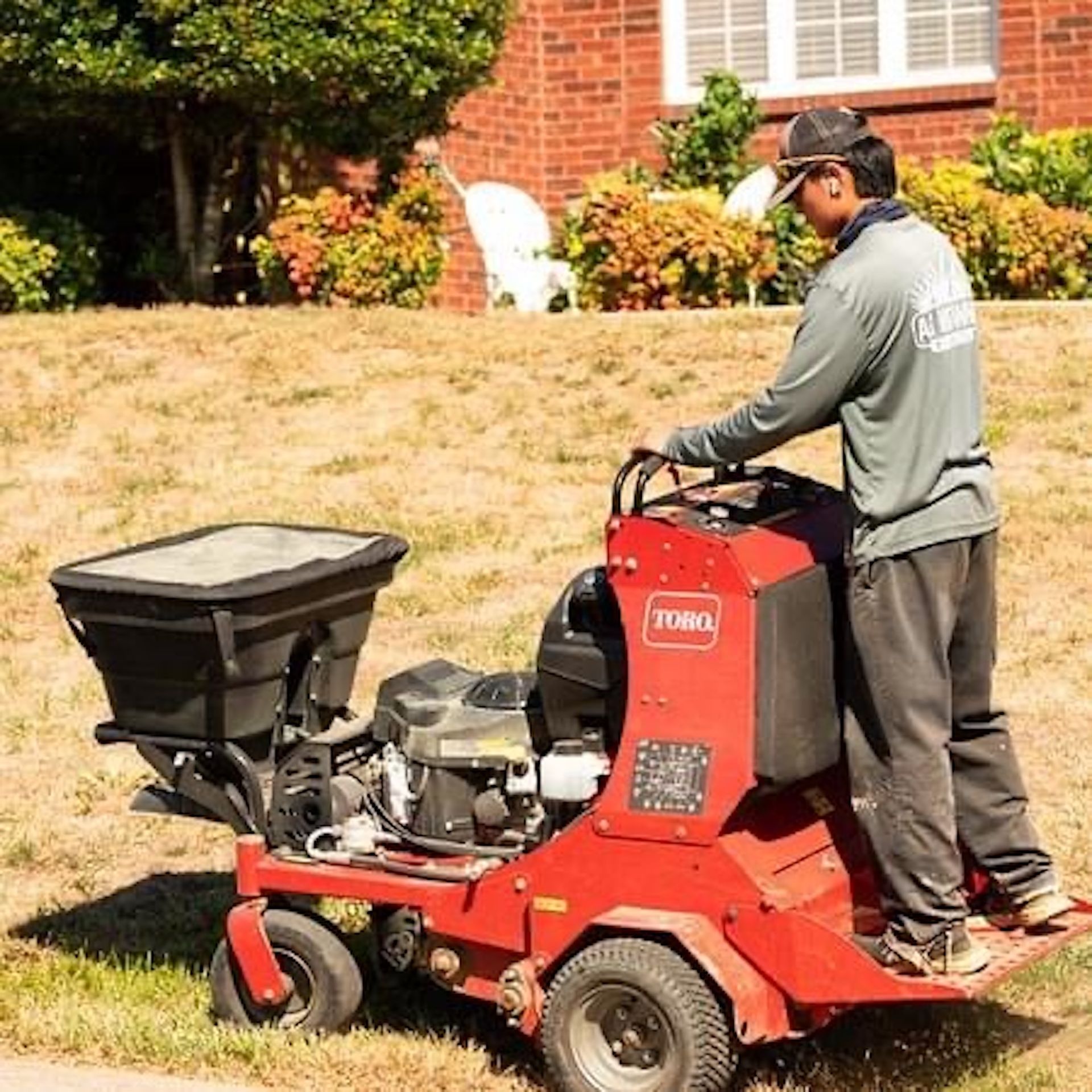 A man is riding a red toro lawn mower