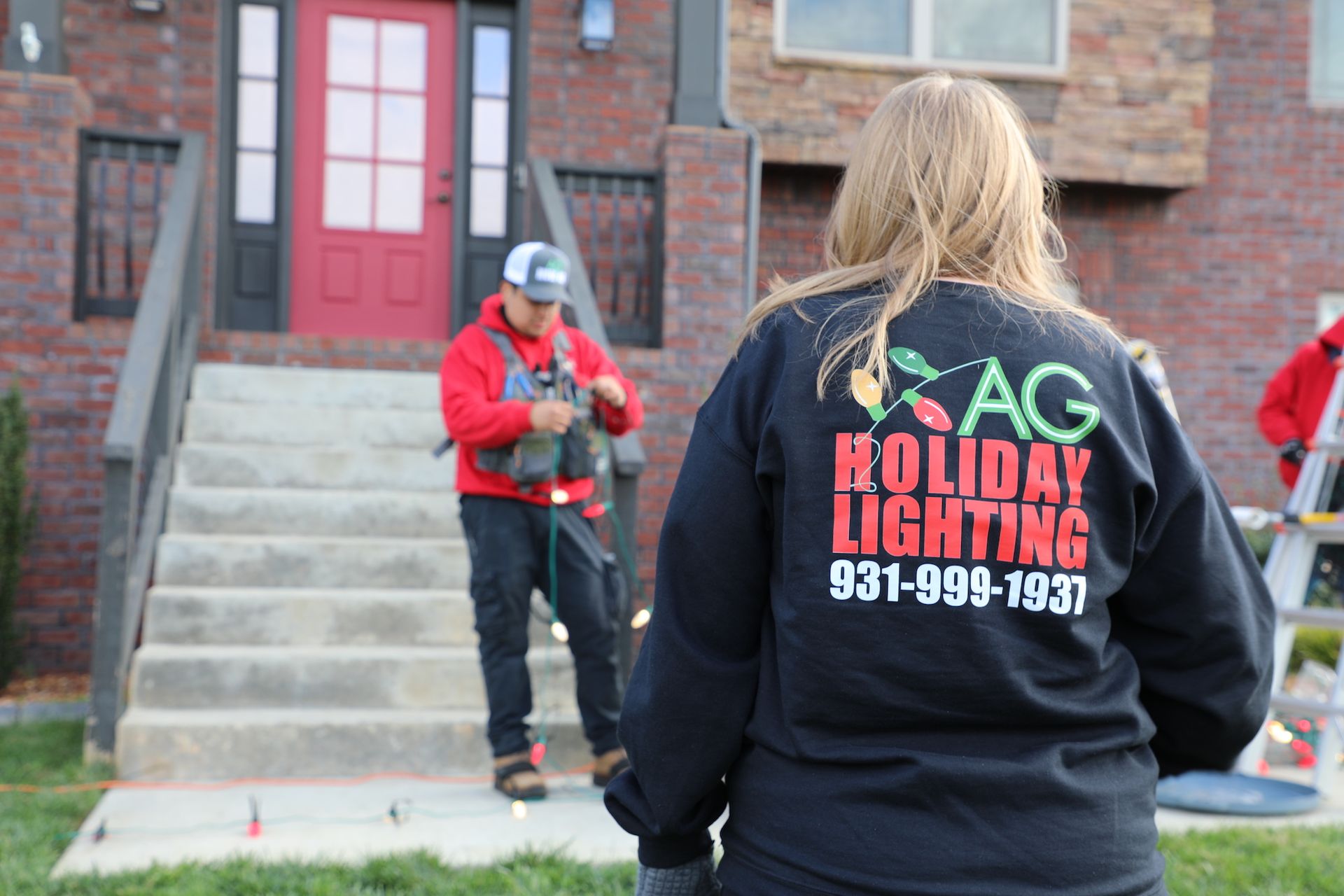 A woman wearing a black shirt that says ag holiday lighting
