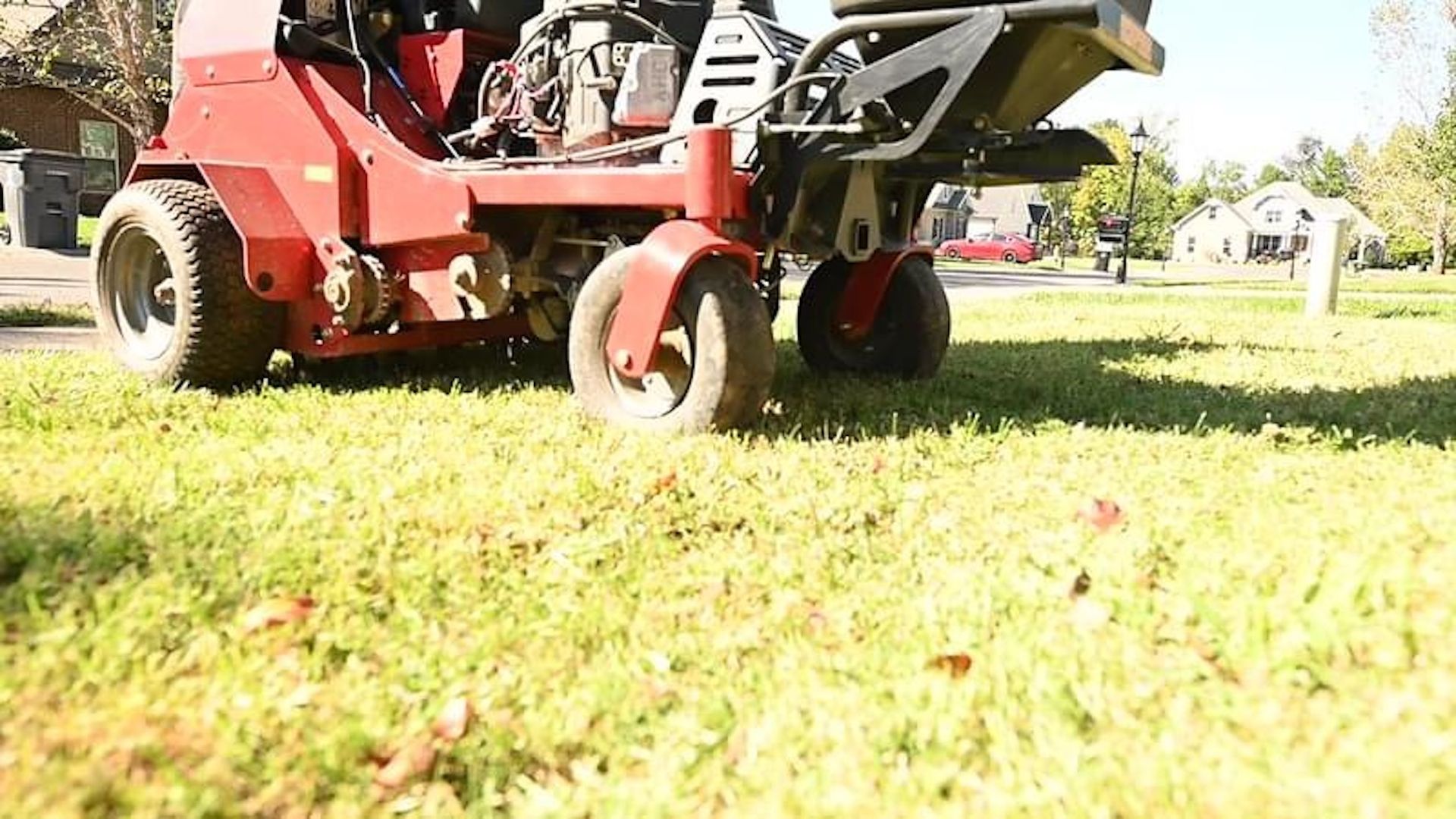 A red lawn mower is cutting a lush green lawn.