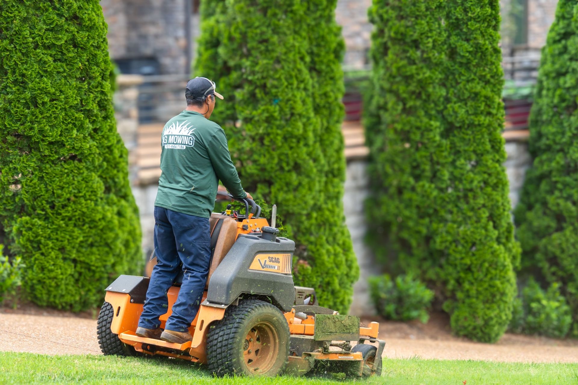 A man is riding a lawn mower on a lush green lawn.