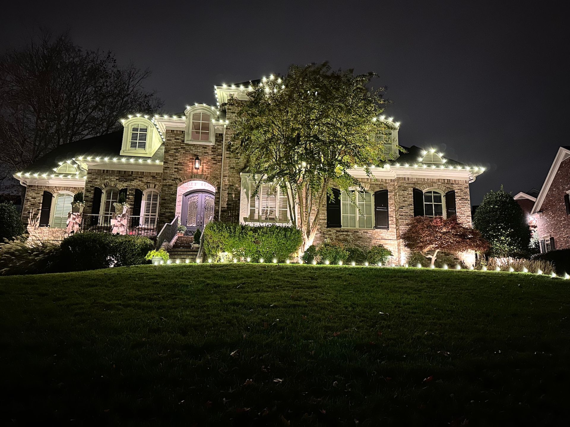 A large house is lit up with christmas lights at night.