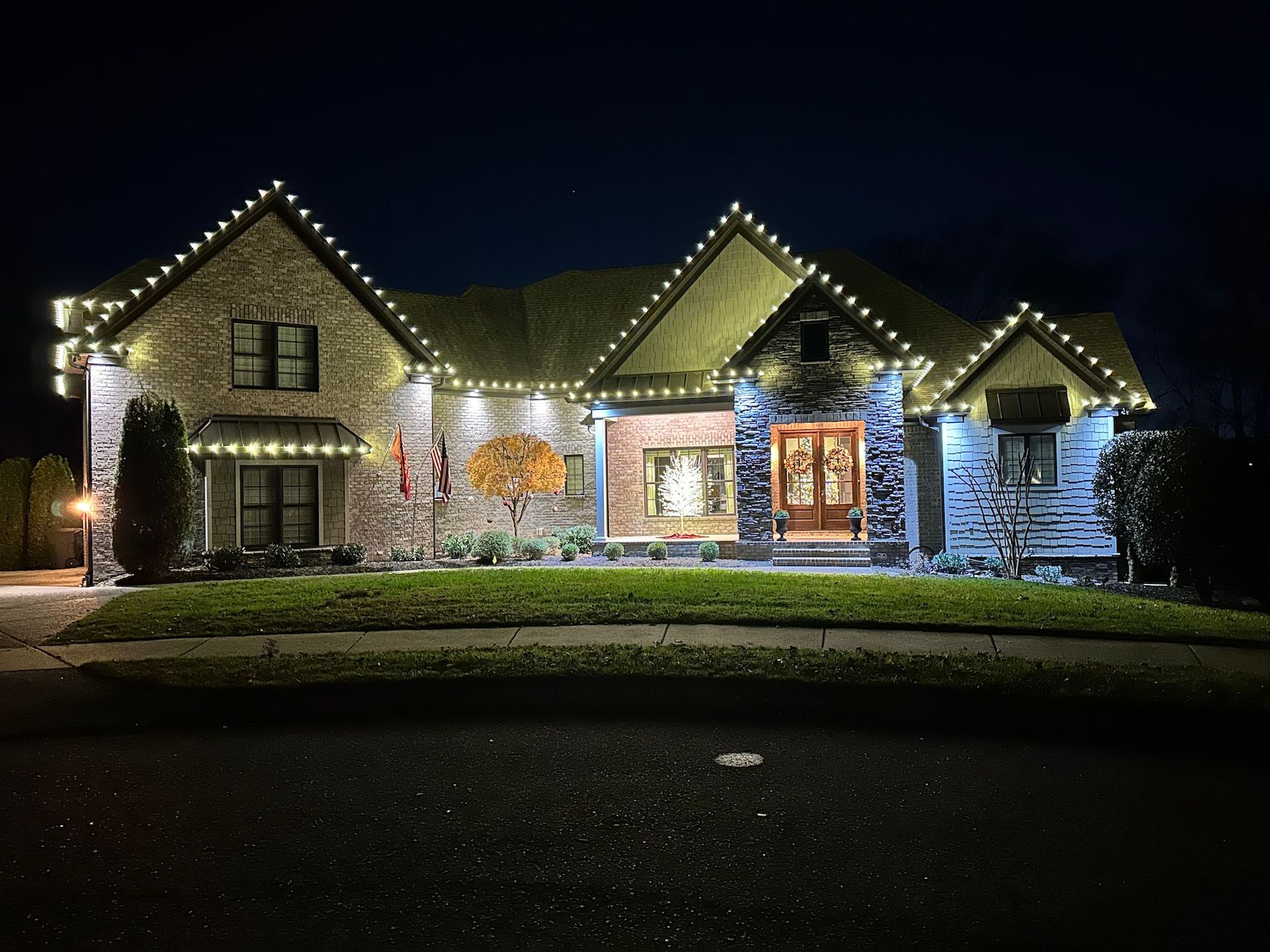 A large house with christmas lights on it is lit up at night.