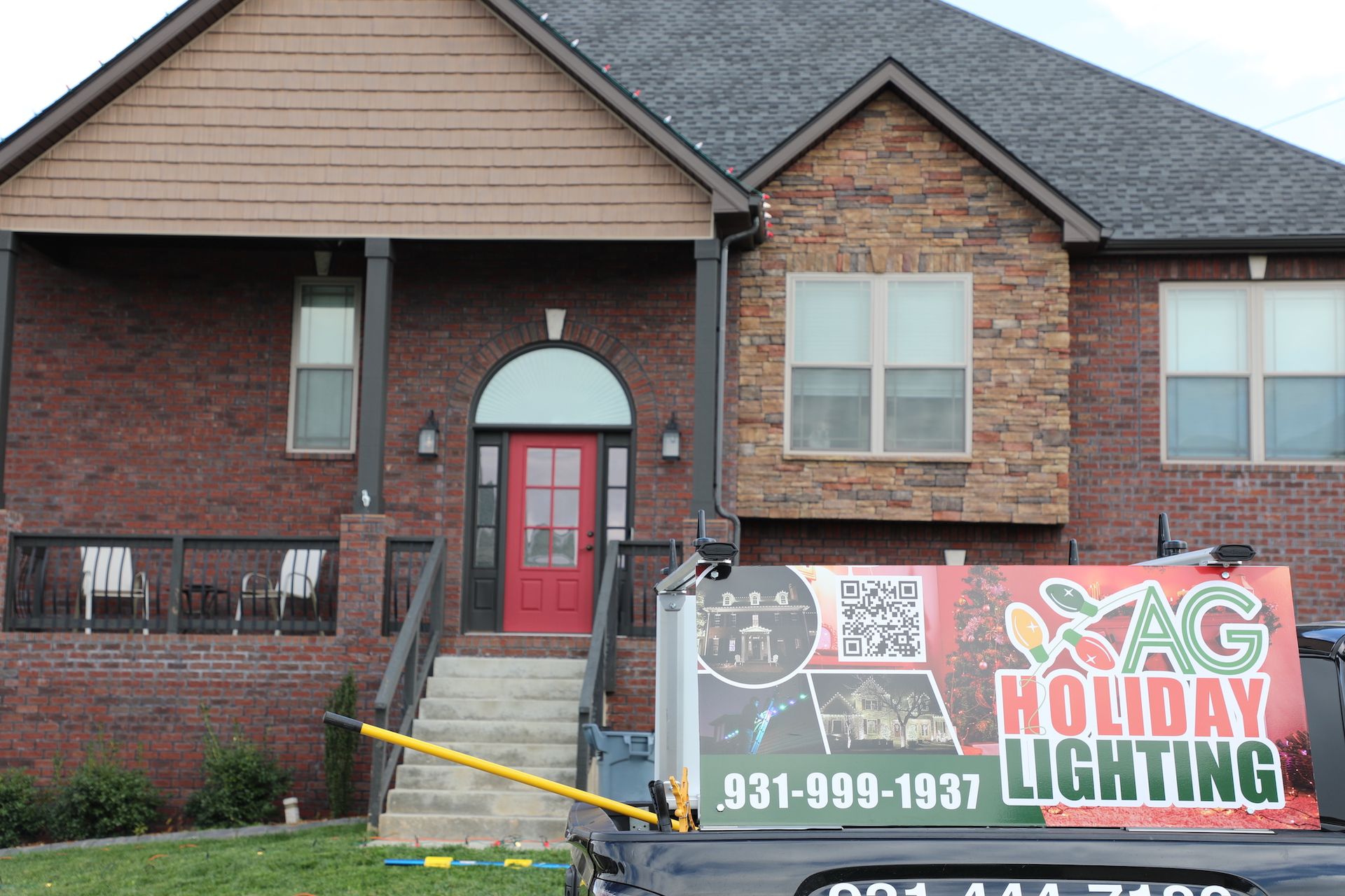 A house with a truck parked in front of it that says holiday lighting