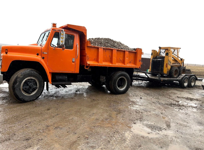 A man is standing in front of a septic pump truck holding a sign that says rapper full.