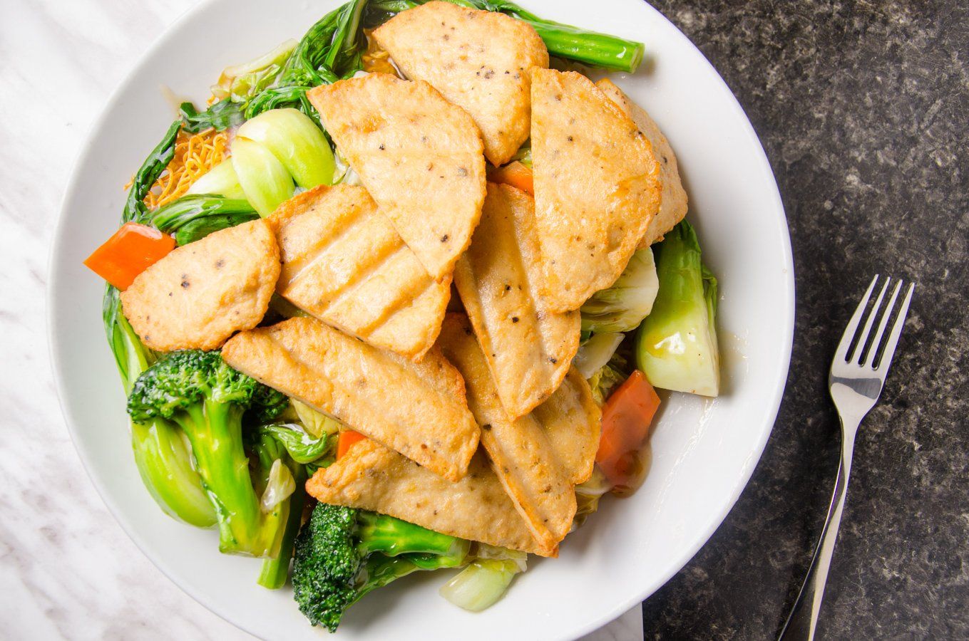 Grilled tofu and vegetables on a plate with a fork.