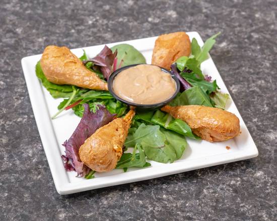Fried tofu and dip on salad, white plate.