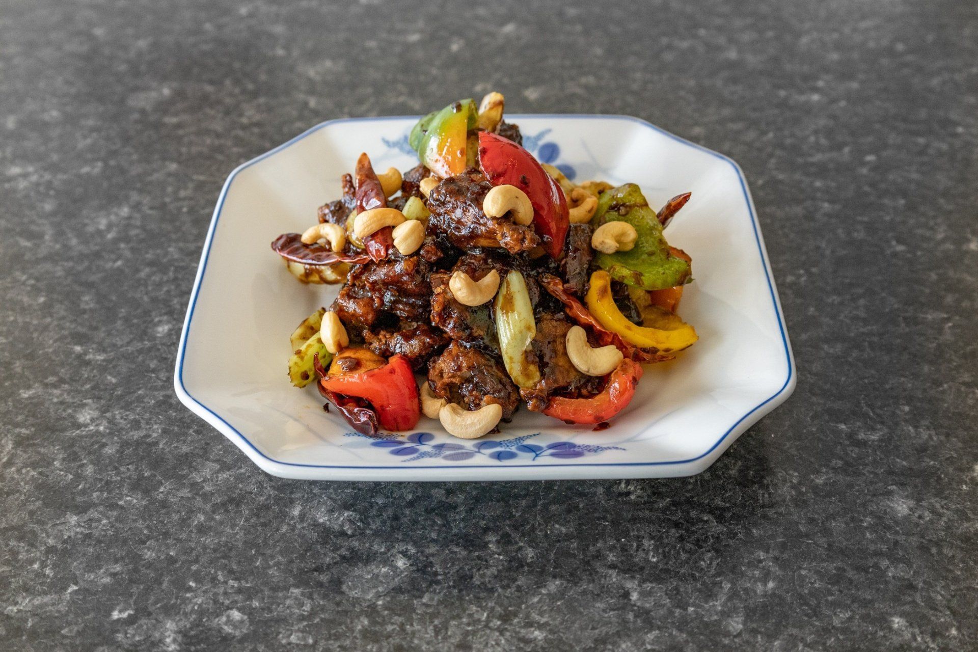 Plate of stir-fry with peppers, cashews, and dark sauce.